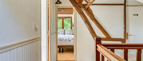 Een houten trap die leidt naar een slaapkamer met een bed en een raam.