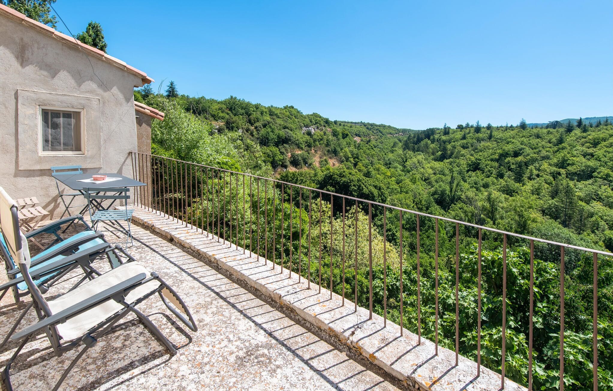 A balcony with outdoor furniture, a table, and a chair.