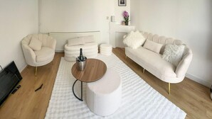 Ein modernes Wohnzimmer mit einem weißen Sofa, zwei Sesseln, einem Couchtisch und einem weißen Teppich.