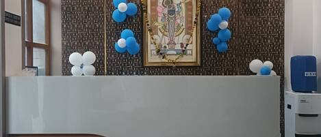 A reception area with a modern design, featuring a patterned wall, a framed artwork, and decorative balloons.