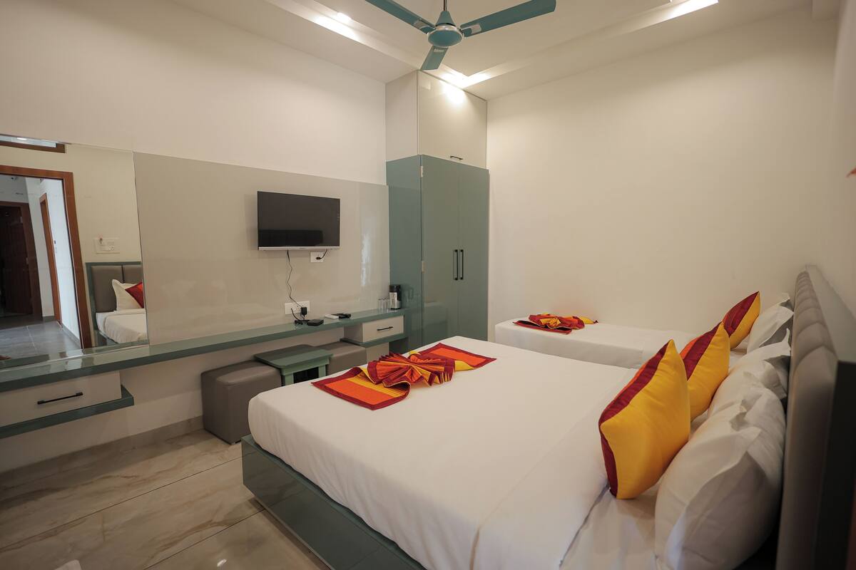 Ein Hotelzimmer mit Bett, Fernseher, Spiegel, Kleiderschrank und Schreibtisch.