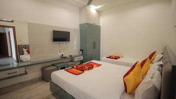 A hotel room with a bed, a TV, a mirror, a wardrobe, and a desk.