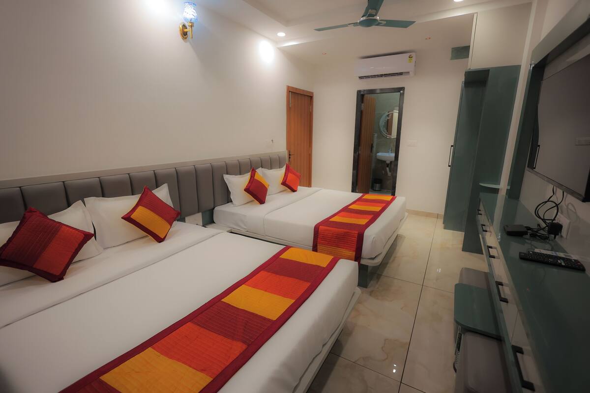 Ein Hotelzimmer mit zwei Betten, einem Fernseher, einem Schreibtisch und einer Badezimmertür.