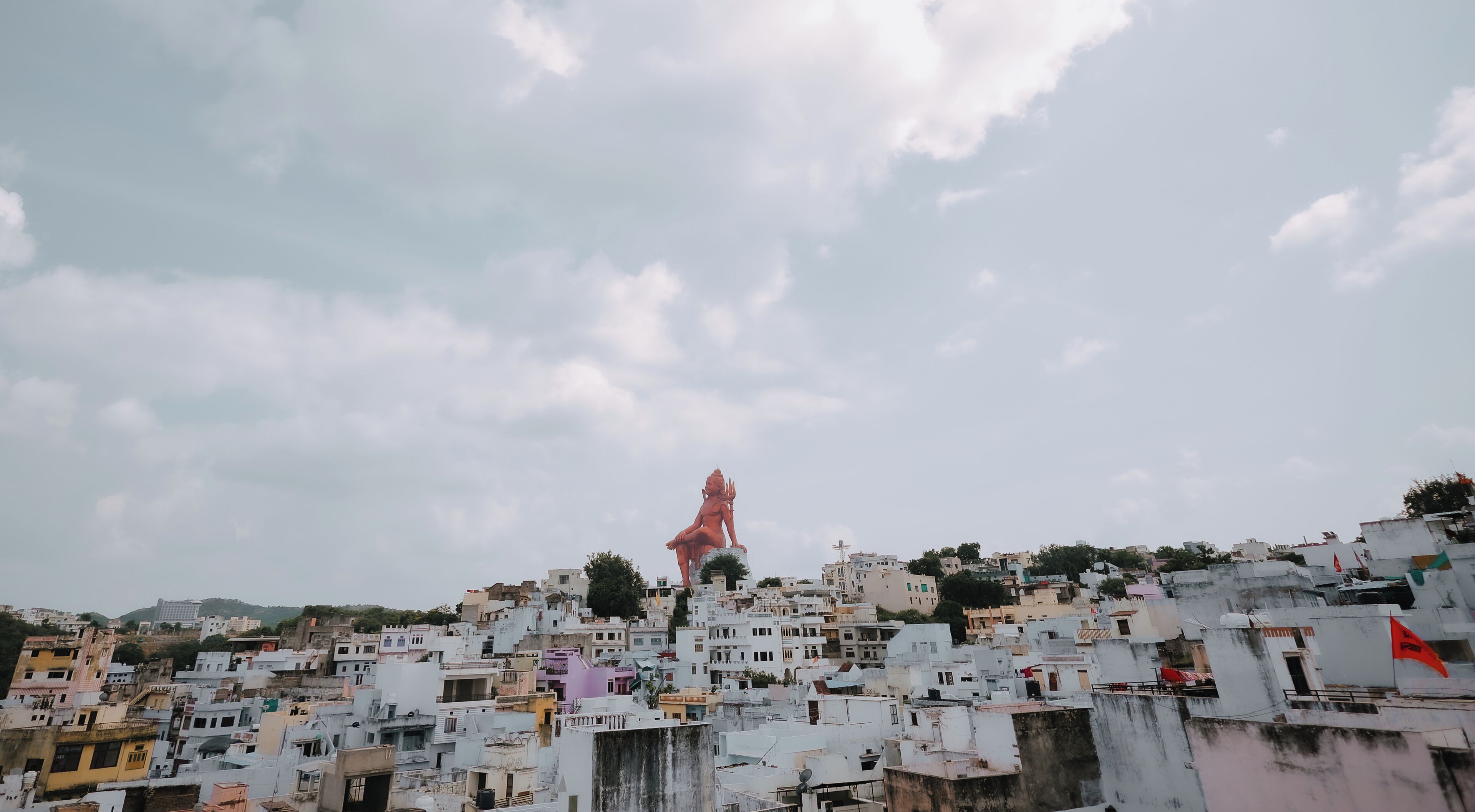 A densely packed urban area with a prominent statue on a hill.