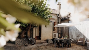 Un coin repas extérieur rustique, avec une table, des chaises et un vélo.