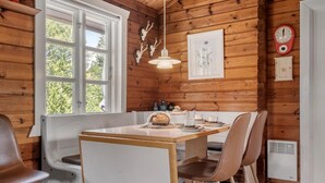 Un interior de madera con una mesa de comedor, sillas, una ventana y un reloj de pared.