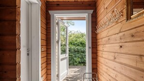 Un pasillo de madera con una puerta que da a un espacio exterior.