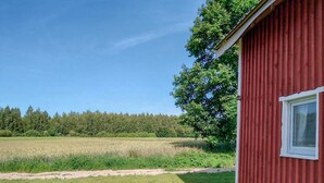 A red building with a window, surrounded by a grassy field and a forest. - 2 bedroom lovely home in Ilawa (Ilawa)
