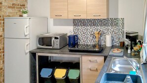 A compact kitchen with a microwave, toaster, and a coffee maker. There are cabinets, a sink, and a tiled backsplash. - 2 bedroom lovely home in Ilawa (Ilawa)