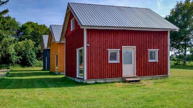 A red wooden cabin with a metal roof, a small porch, and a door. - 2 bedroom lovely home in Ilawa (Ilawa)