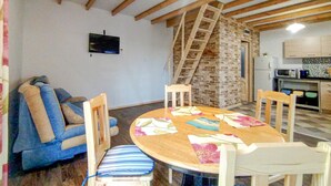 A cozy living room with a round wooden table, blue and white striped sofa, and a brick wall with a wooden ladder. - 2 bedroom lovely home in Ilawa (Ilawa)