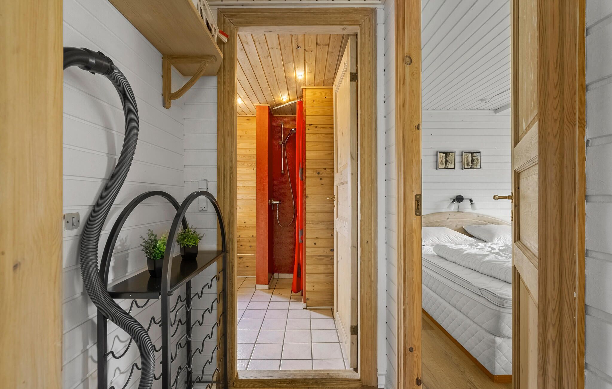 Un corridoio stretto che conduce a una camera da letto con un letto, un soffitto in legno e un pavimento piastrellato.