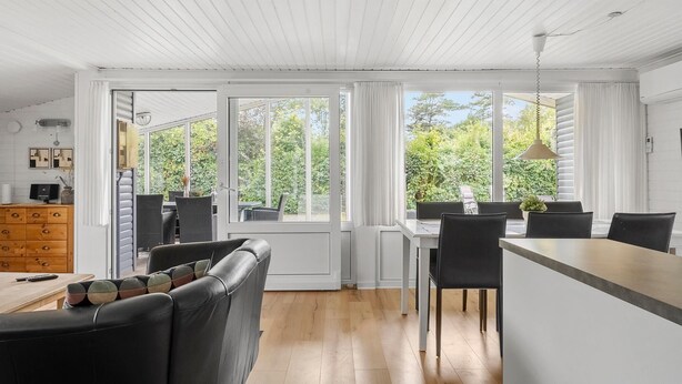 Eine moderne Küche mit Essbereich, großen Fenstern und Blick auf Grünflächen.