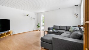 Ein modernes Wohnzimmer mit einem Ecksofa, einem Flachbildfernseher und Holzboden.