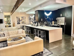 Una cocina moderna con una isla central, taburetes de bar y un refrigerador.