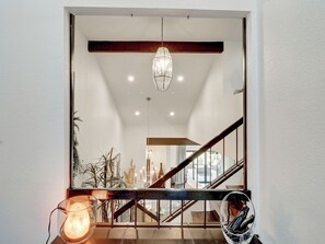 Un interior moderno con una escalera de madera, una lámpara colgante y una mesa de vidrio con una vela.