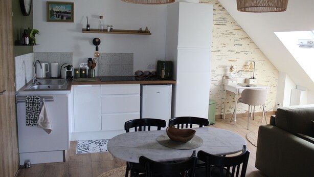 A compact kitchen with a dining area, a small refrigerator, and a window providing natural light.