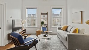 Un salon moderne avec un canapé, des fauteuils, une table basse et un téléviseur.