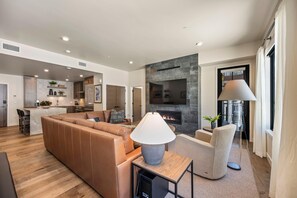 A modern living room with a leather sofa, a TV mounted on a stone wall, and a fireplace. - Slopeside | Exclusive Tamarack Perks (Tamarack)