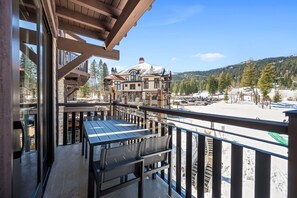 A balcony with a view of a snow-covered landscape and a building with a sloped roof. - Slopeside | Exclusive Tamarack Perks (Tamarack)