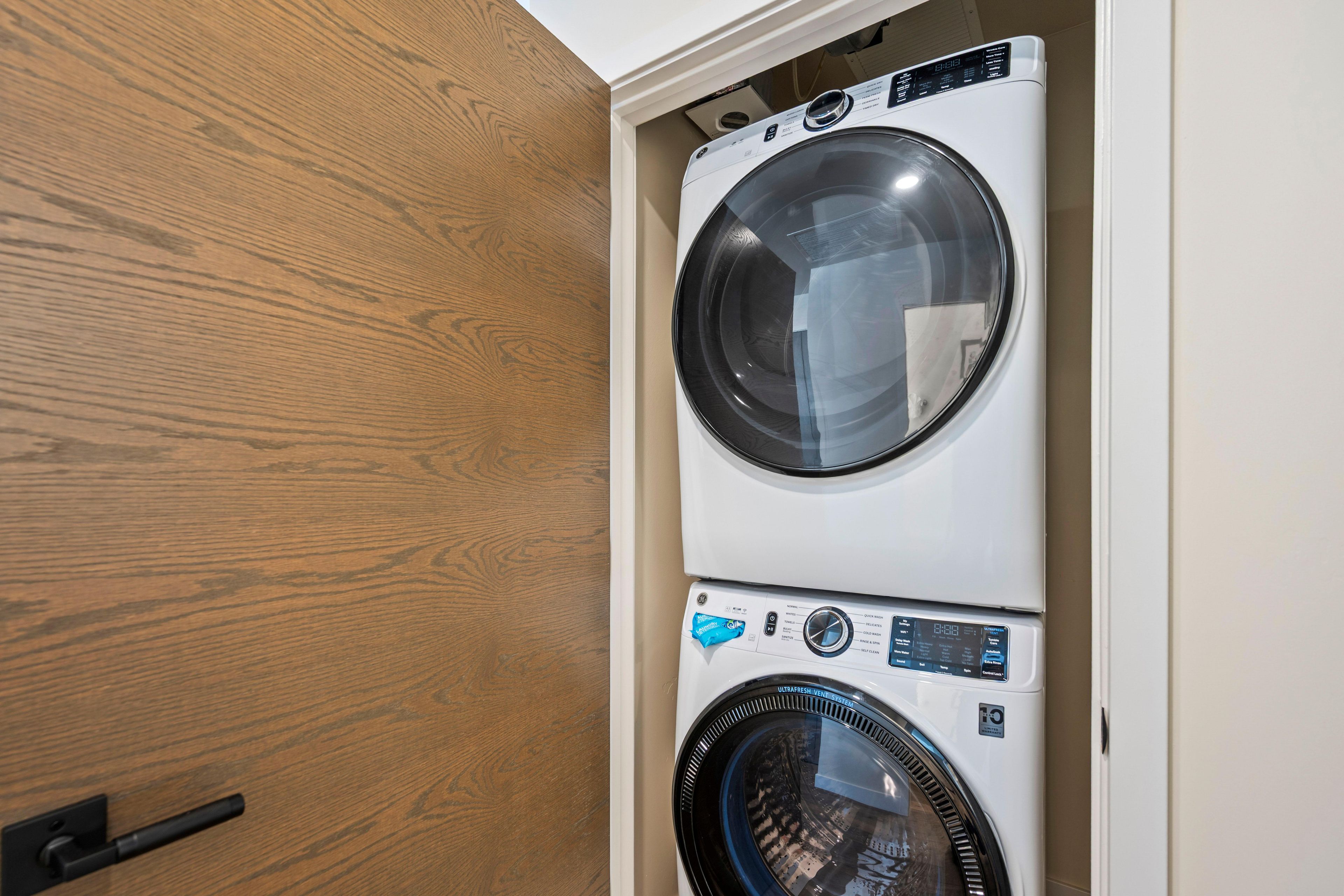 A stacked washer and dryer unit with a wooden door and a visible handle.