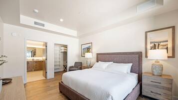 Une chambre spacieuse avec un grand lit, une table de chevet, une lampe et un tableau encadré au mur.
