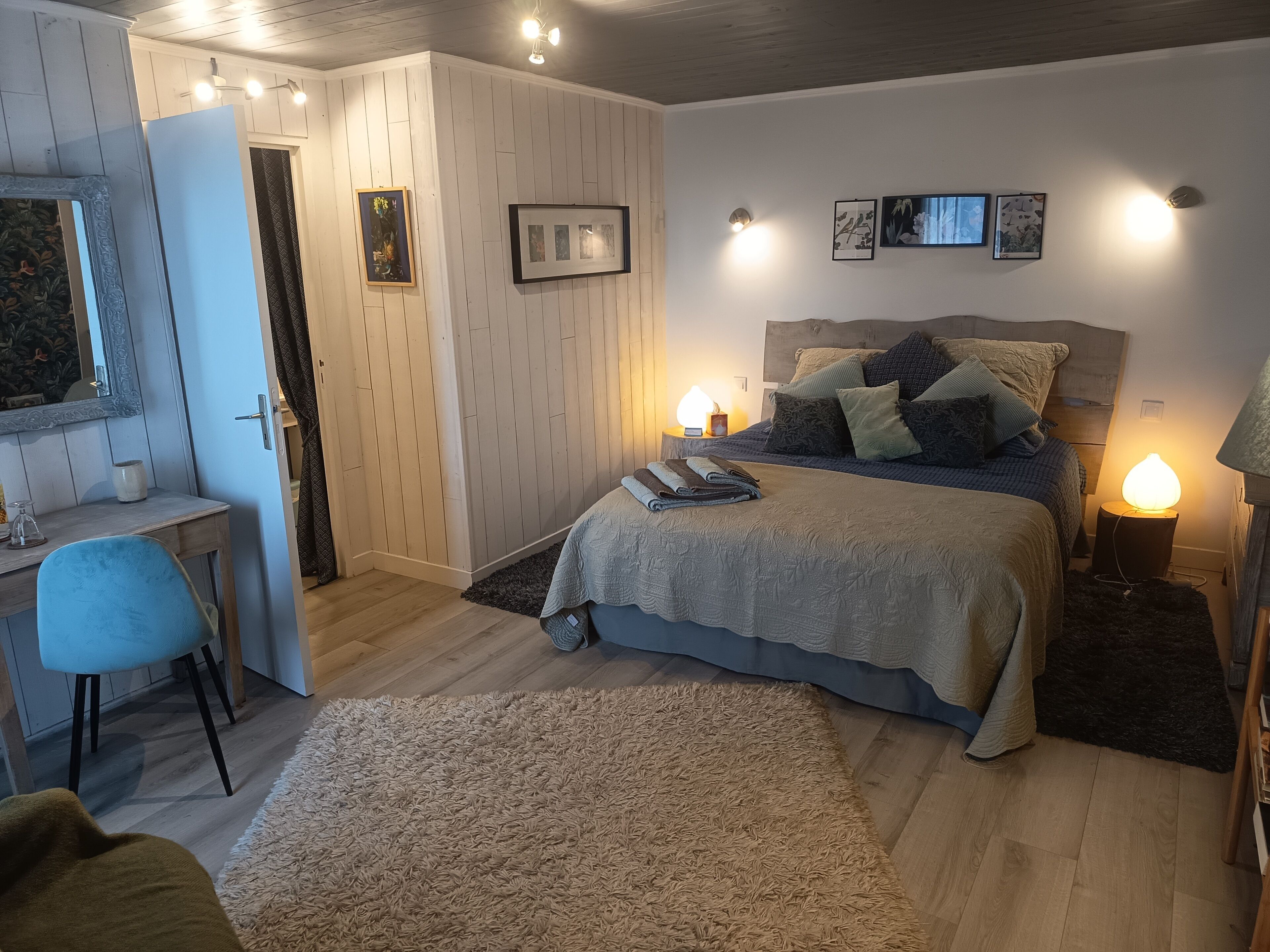 Quarto com cama, abajures, escrivaninha e uma cadeira.
