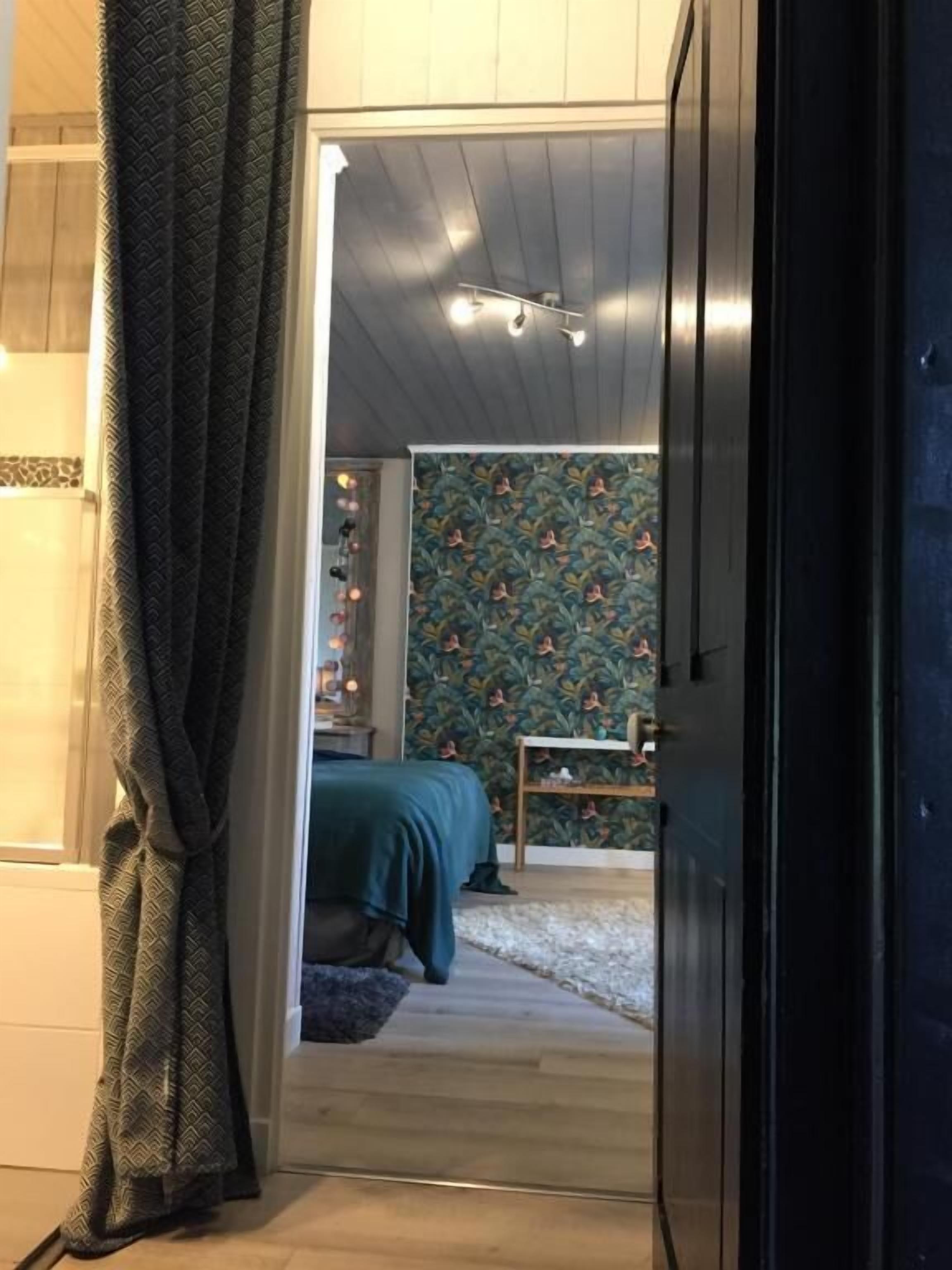 Un dormitorio con cama, mesita de noche, cómoda y papel tapiz estampado.