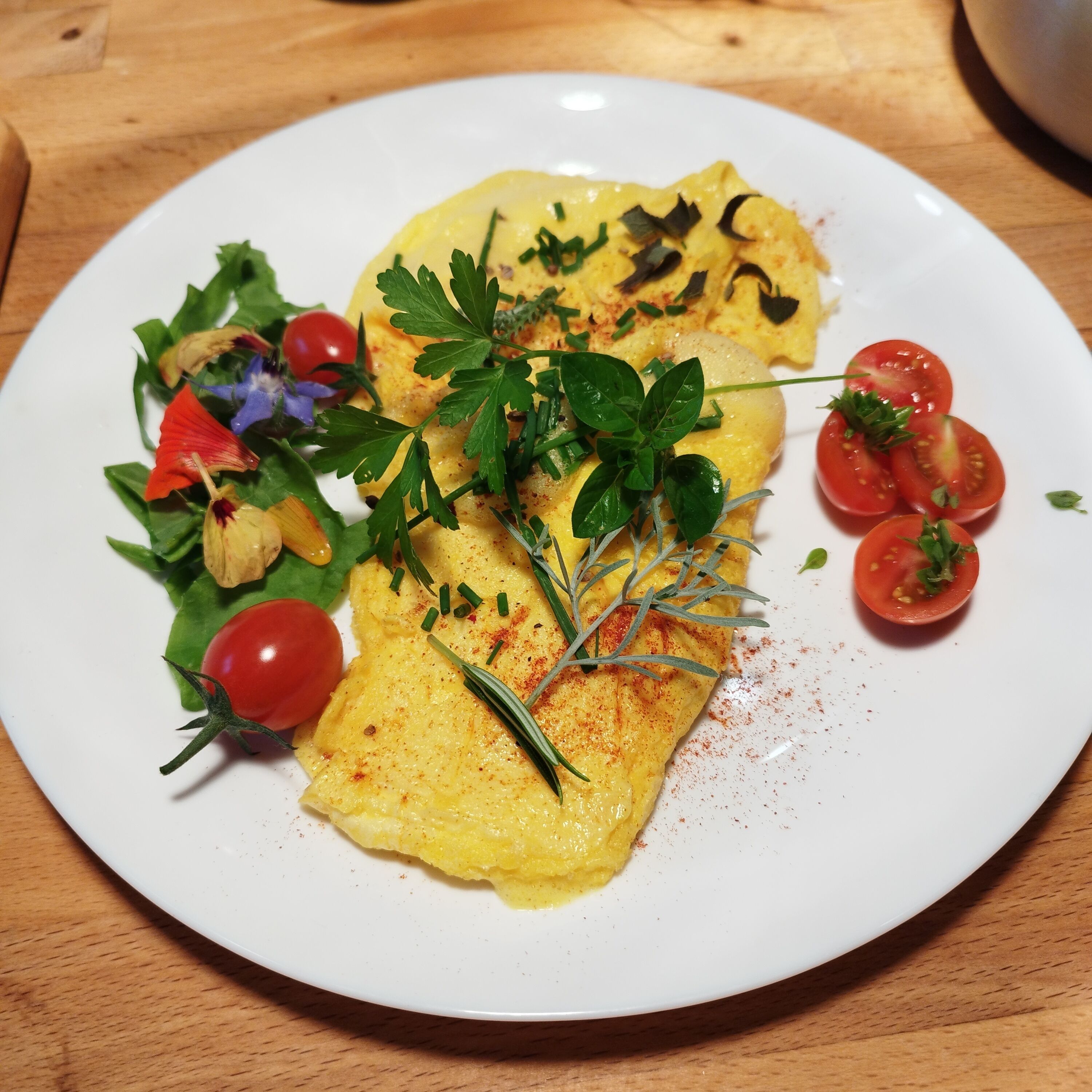 Un plato con tortilla, tomates cherry y una ensalada.
