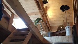 A wooden interior with a loft area, a staircase, and a door leading to another room. - Les 3 Koïs (Riec-sur-Bélon)