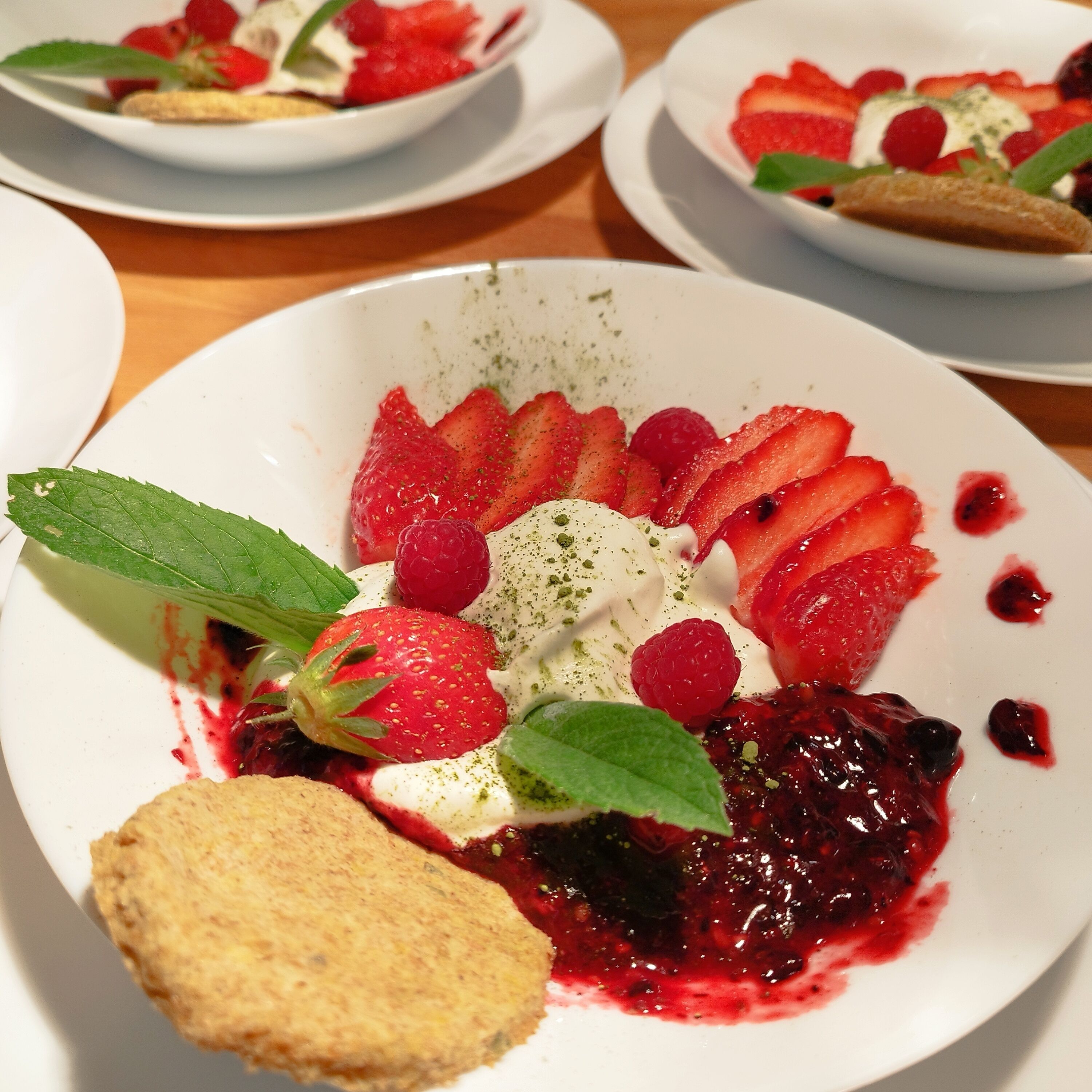 A dessert plate with strawberries, raspberries, whipped cream, and a berry compote.
