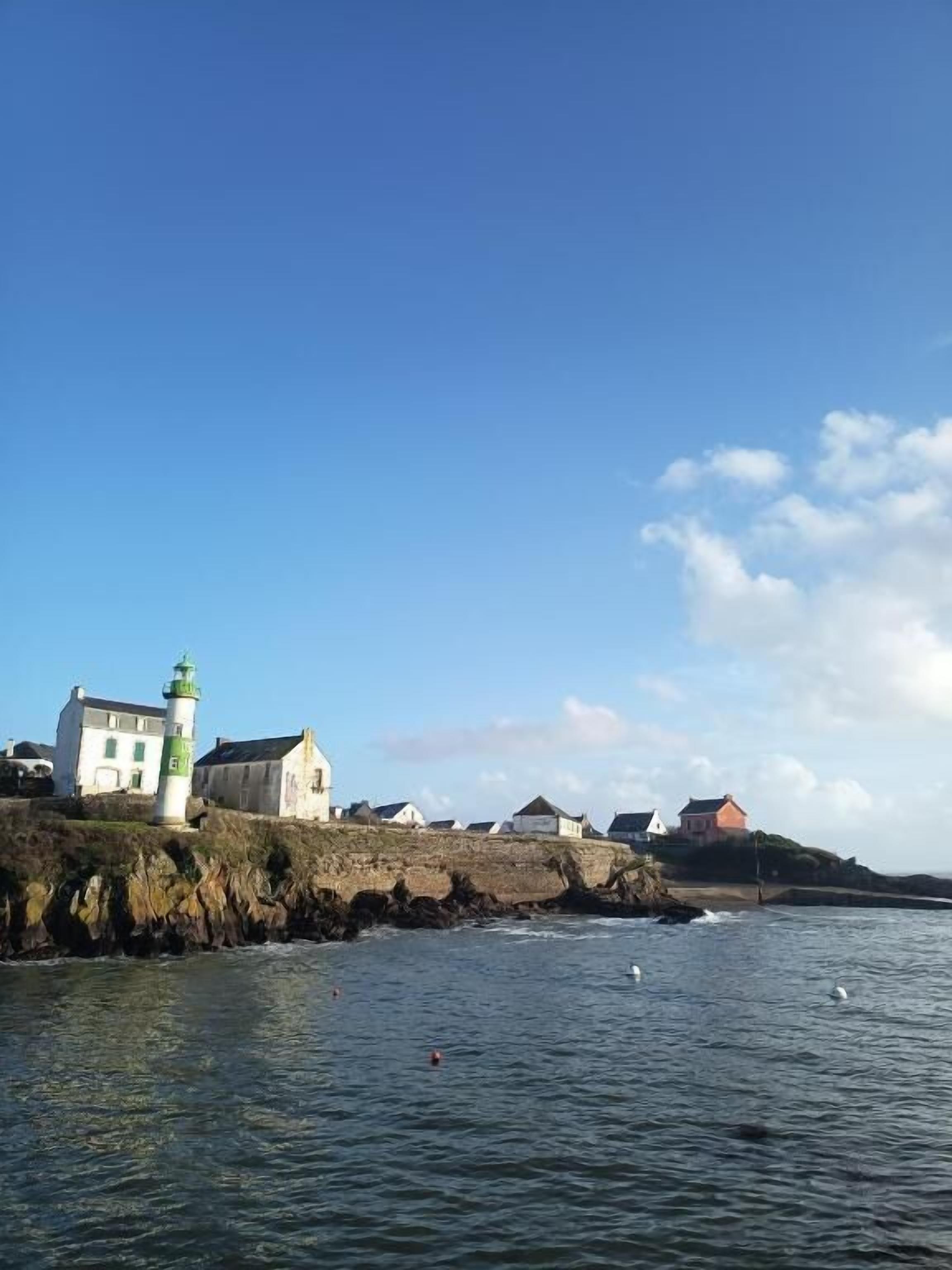 Eine Küstenansicht mit einem Leuchtturm, weißen Gebäuden und einer felsigen Küste.