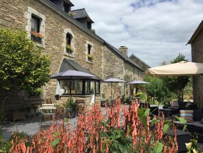 A stone building with outdoor seating and umbrellas. - Les 3 Koïs (Riec-sur-Bélon)