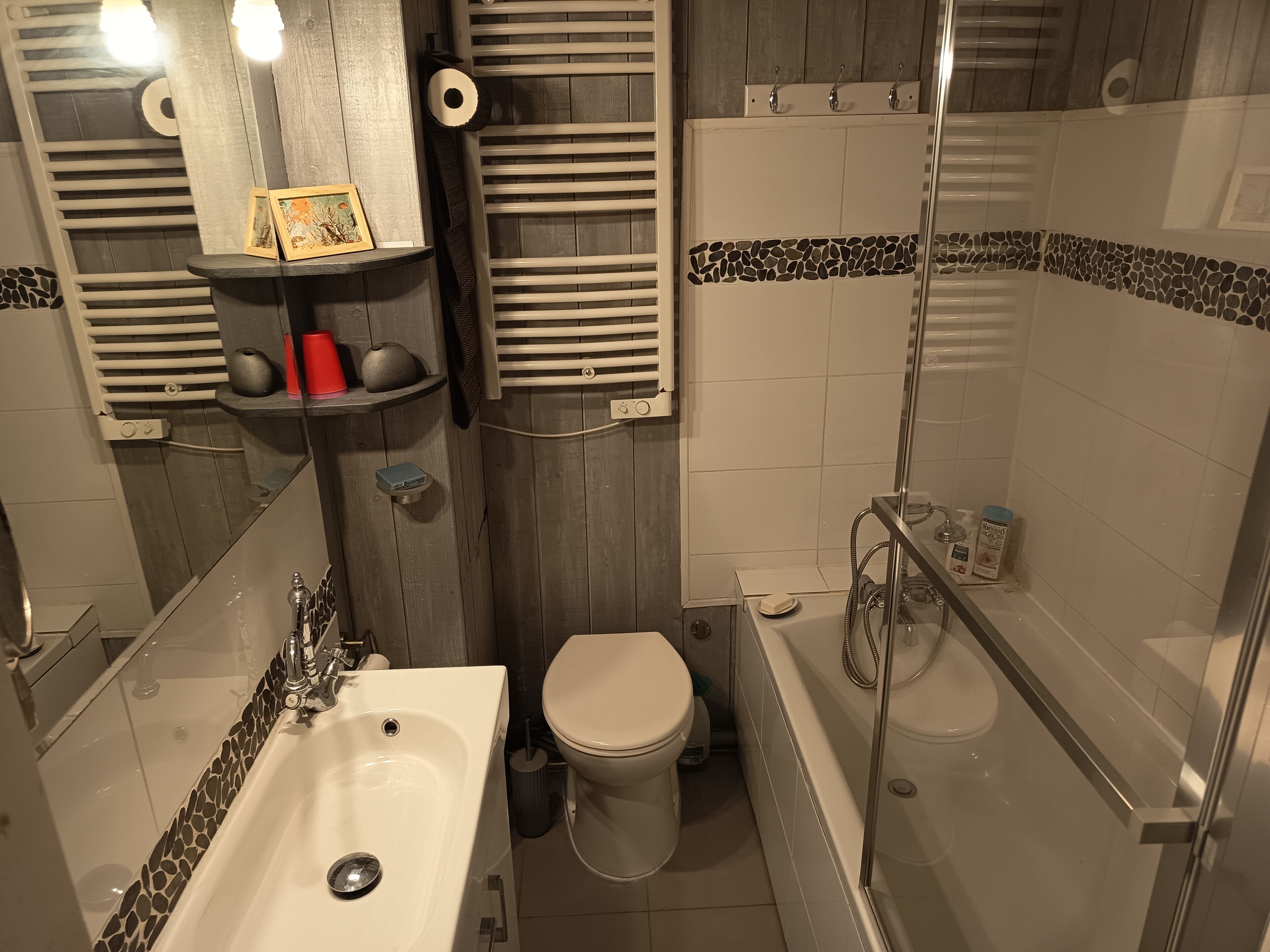 A bathroom with a shower, toilet, sink, and towel rack.