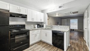 A modern kitchen with white cabinets, a black stove, and a dishwasher.