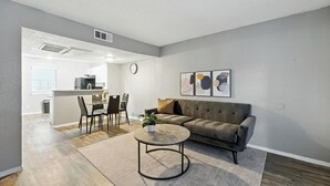 A modern living room with a sofa, coffee table, and dining area.