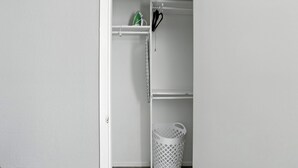 A white closet with shelves, a hanging rack, and a laundry basket.