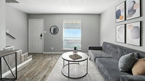 A modern living room with a grey sofa, a coffee table, and artwork on the wall.