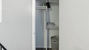 A closet with a hanging rack, shelves, and a laundry basket.