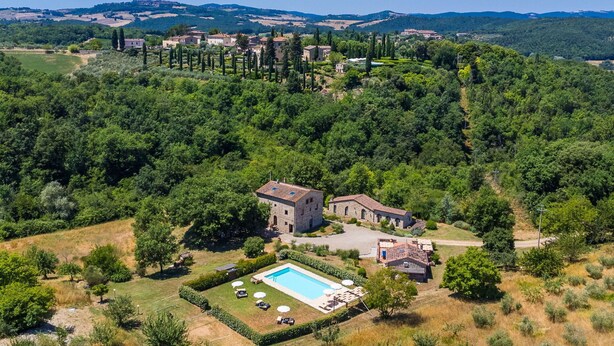 Vista aérea de una villa con piscina, rodeada de exuberante vegetación y colinas al fondo.