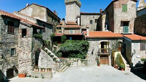 A historic stone building with a tower, a courtyard with steps, and a small gate. - Beautiful apartment in villa for 5 guests with pool, A/C, WIFI, terrace and pets allowed (Capalbio)