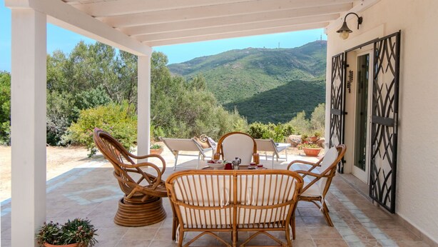 A covered outdoor seating area with wicker furniture and a view of a mountainous landscape. - Stunning private villa for 4 people with WIFI, A/C, TV, patio, pets allowed and panoramic view (Olbia)