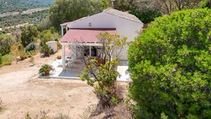 A white house with a red roof, surrounded by greenery and hills in the background. - Stunning private villa for 4 people with WIFI, A/C, TV, patio, pets allowed and panoramic view (Olbia)