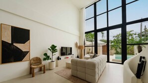 Un salon spacieux doté d’une grande fenêtre, d’un téléviseur à écran plat, d’un canapé confortable, d’une table basse et d’une plante en pot.