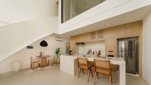 Une cuisine moderne dotée d’un îlot central, de meubles en bois et d’un réfrigérateur en acier inoxydable.