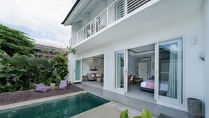 Una casa moderna con piscina, balcón y una habitación con cama y escritorio.