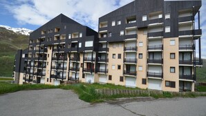A multi-story building with balconies and a parking area in front. - Studio for 4 at 3 Valleys Ski-in/Ski-out (Les Menuires)