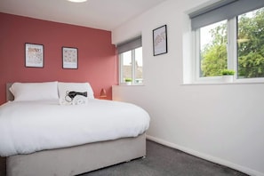 A bedroom with a bed, a window with a view, and two framed pictures on the wall. - Vacant Nests | The Darwin | Stylish | Wifi (Hartlepool)