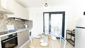 A modern kitchen with a dining area, featuring a built-in oven, microwave, and a washing machine. - Barn La Roca Masia - Les Pivoines, swimming pool, garden, 1 bedroom 2/4 persons (Assier)