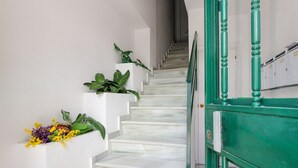 A staircase with white steps and green railings, leading to a landing with a white wall and a small plant with yellow flowers. - Los Boliches apartment - central location (Fuengirola)